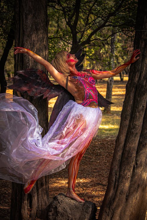 A woman in a dress and skirt is posing in the woods