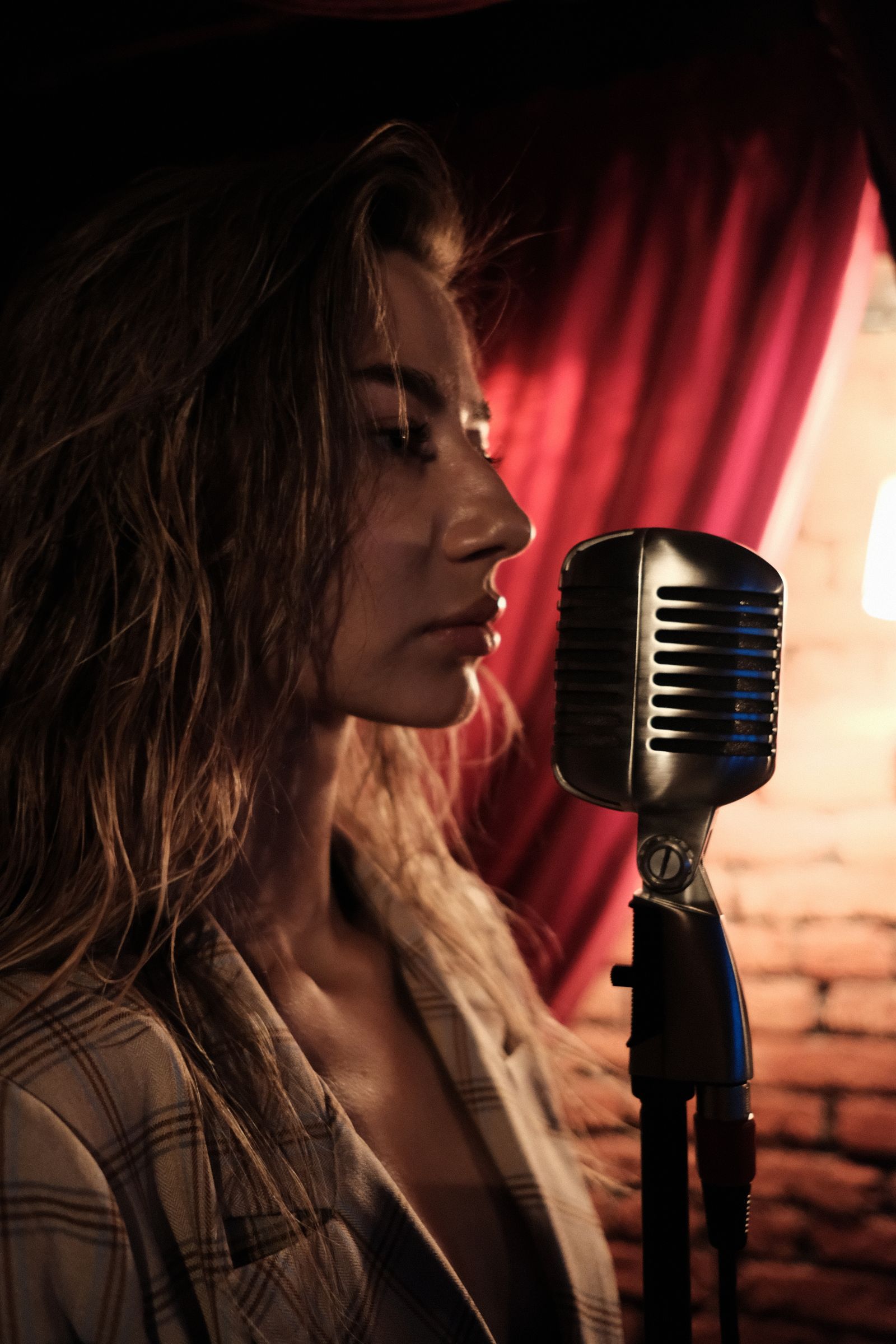A singer at a microphone in front of a red curtain
