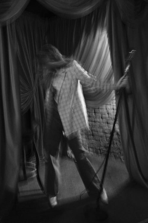 A woman is standing in front of a curtain