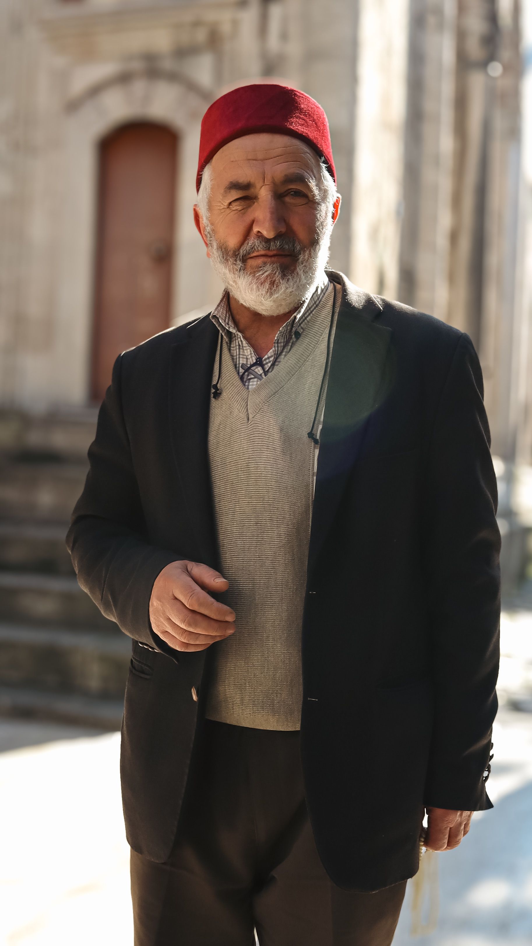 Portrait of a Turkish man wearing a fez, standing in an İstanbul street, embracing cultural attire.