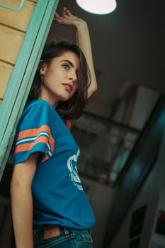 一位年轻女子身着充满活力的蓝色衣服，在室内自信地摆出造型，尽显个人风格