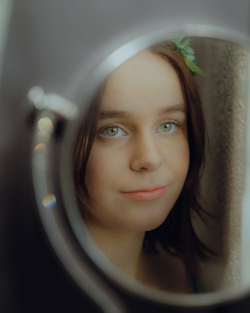 A girl with green eyes looking in a mirror