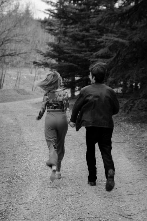 A black and white photo of a couple running down a dirt road