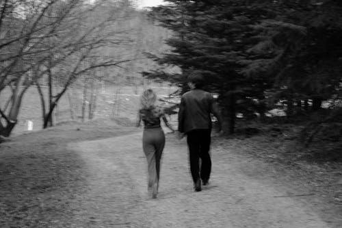 A black and white photo of a couple walking down a path