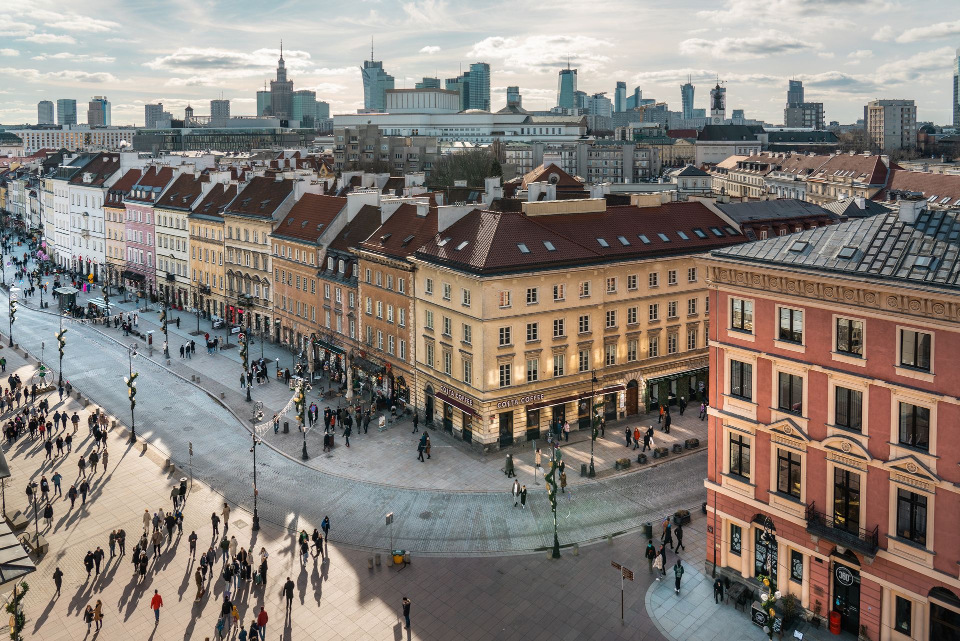 Historic Castle Square and Royal Route façades with pedestrians below Warsaw's Palace of Culture and modern glass skyline, Poland