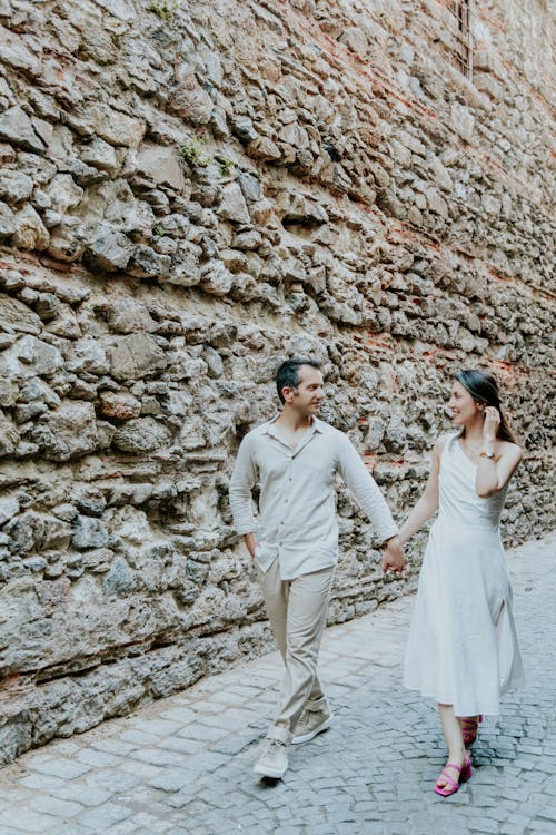 Elegant Couple Walking on a Sidewalk and Holding Hands