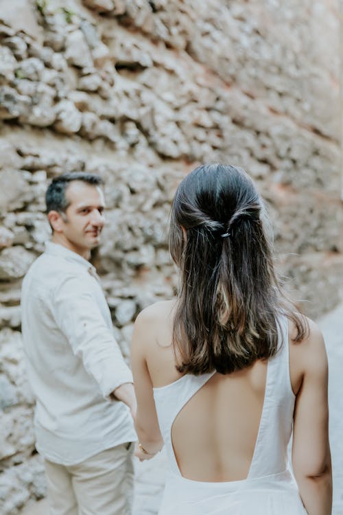 A Couple Walking on a Sidewalk and Holding Hands