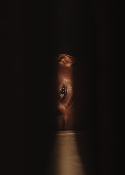 A man's face peeking out from behind a door