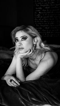 Glamorous black and white portrait of a woman lying on a bed, exuding elegance and style.