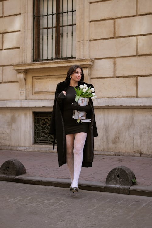 Woman in Black Coat Walking with Flowers on Street in Istanbul