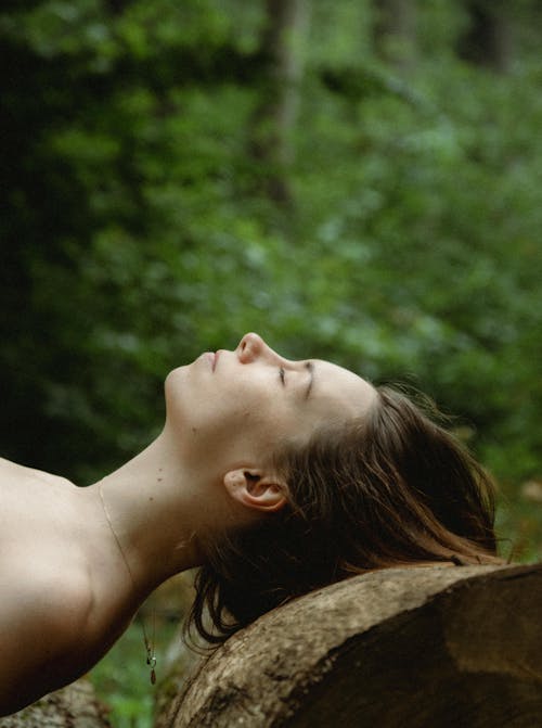 A woman laying on a log in the woods