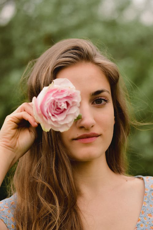 A woman holding a rose in front of her face