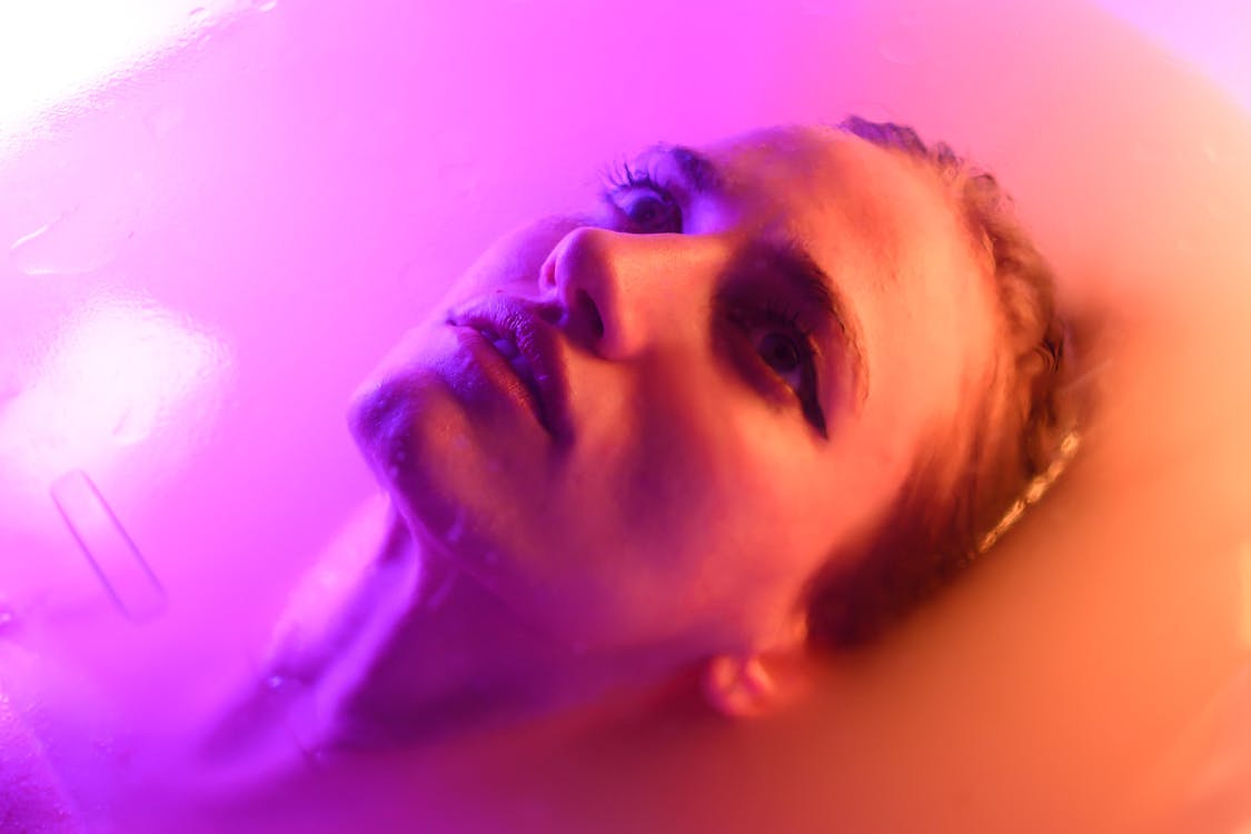 A woman in a bathtub with purple lights