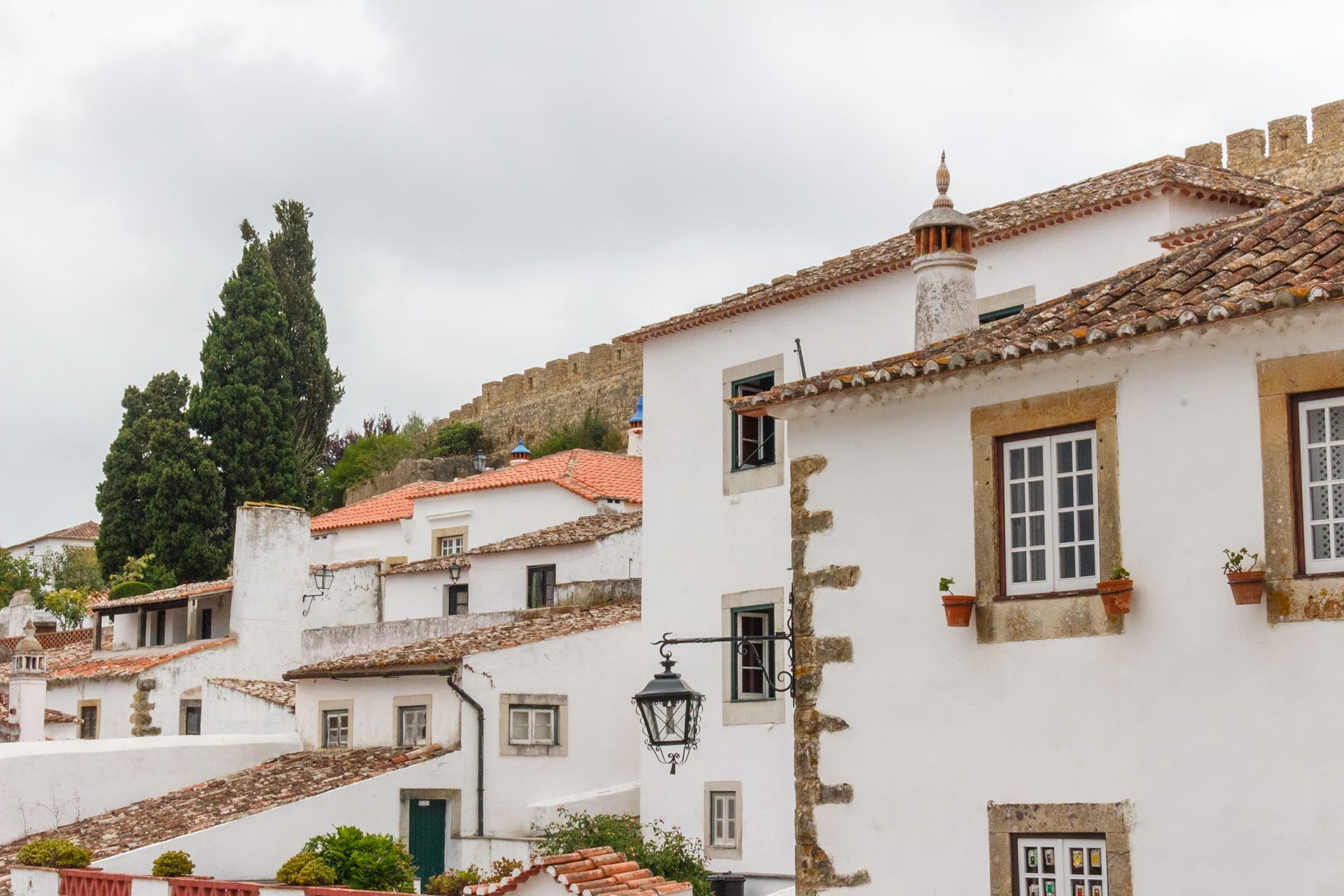 Explore the quaint whitewashed houses and medieval walls of Óbidos, Portugal, captured in this scenic photo.