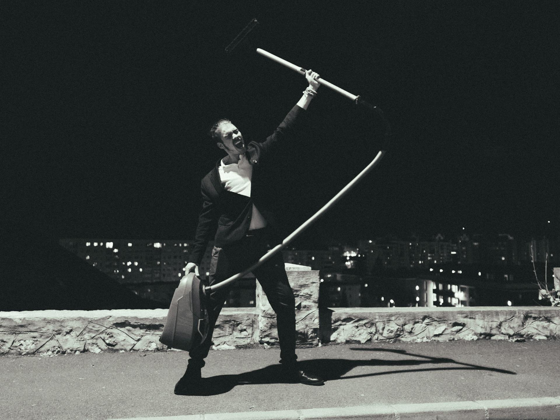 Man in Suit Shouting and Holding Vacuum Cleaner at Night