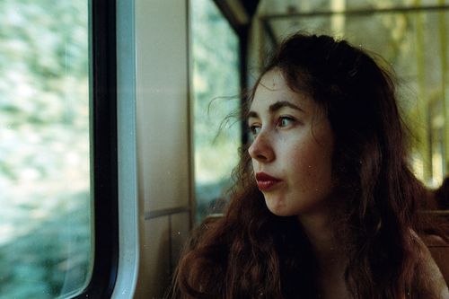 Free A contemplative young woman gazes out a train window, capturing the essence of travel and reflection. Stock Photo