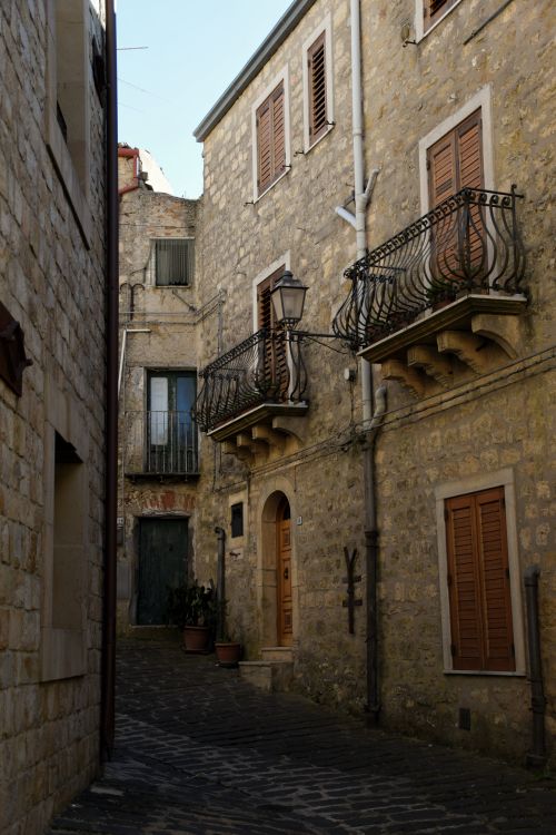 Free Explore a narrow medieval alley with stone buildings and balconies in Gangi, Sicily. Stock Photo