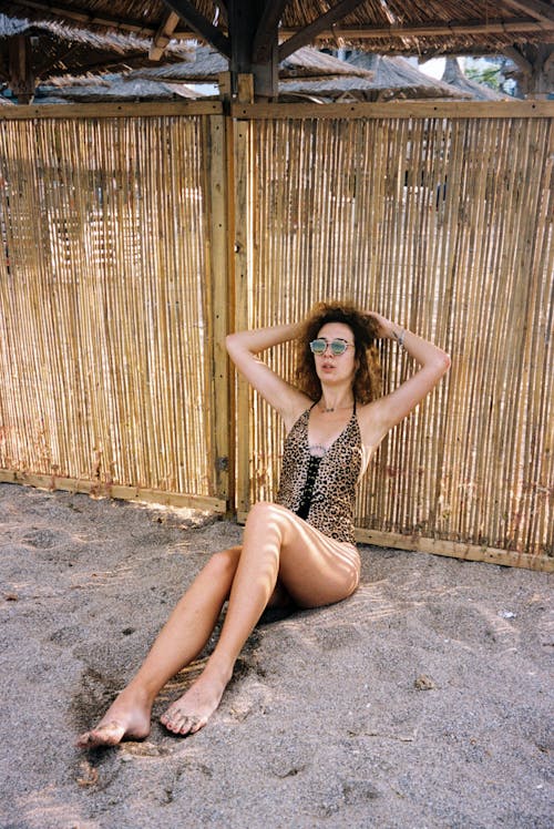 Woman Sitting by Fence on Beach