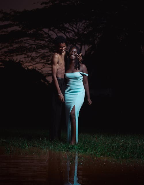 A Shirtless Man and a Woman in a Dress Posing Outside at Dusk 