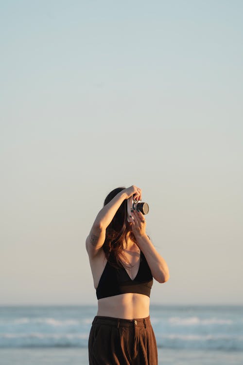 Woman in Bra Taking Pictures on Sea Shore