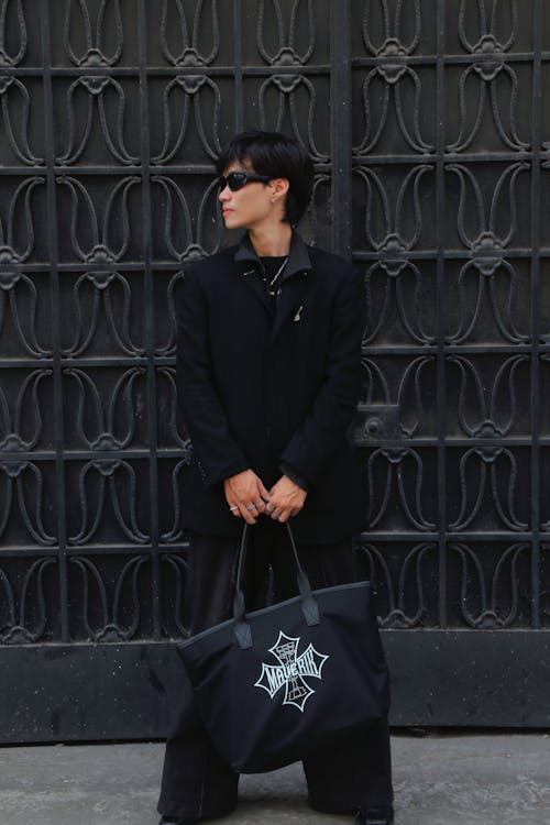 A man in black holding a large tote bag