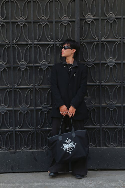 A woman in black holding a black bag