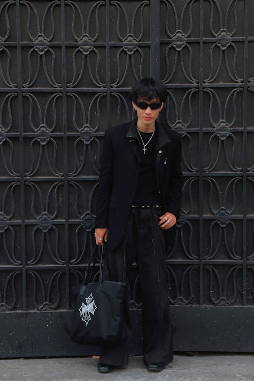 A man in black jacket and pants standing in front of a gate