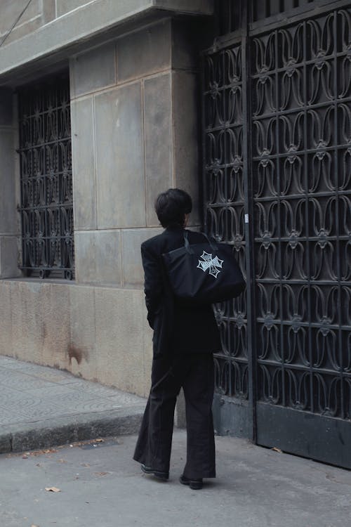 Passerby with a Black Bag Walking Past the Gate