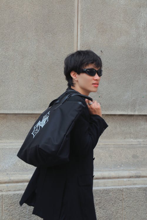 A woman in sunglasses and a black coat carrying a black bag