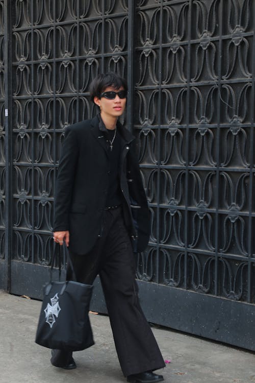 A man in black suit and sunglasses walking down the street
