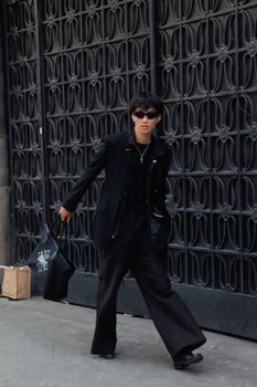 Fashionable adult in black attire strolling through urban area. Trendy city fashion scene.