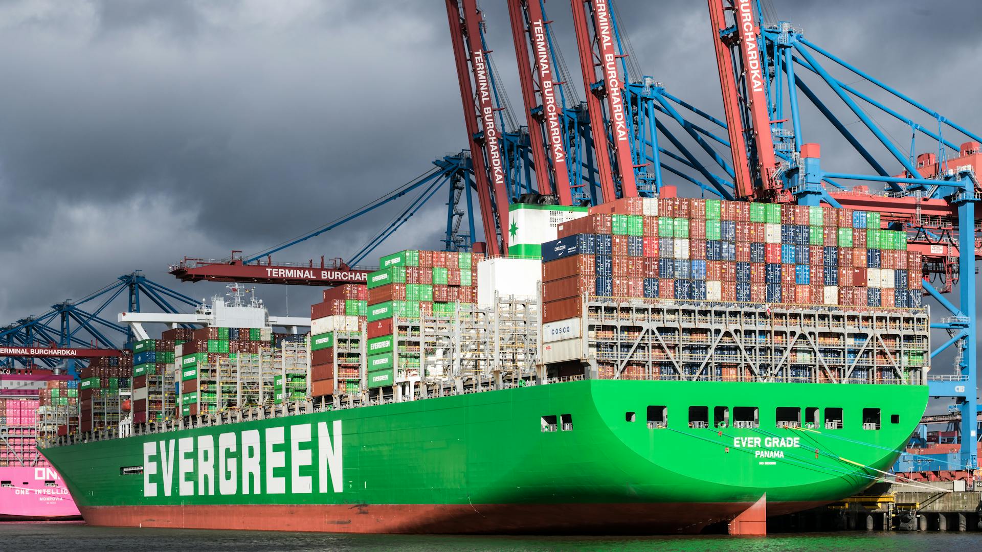 Evergreen cargo ship docked at Terminal Burchardkai, Hamburg under dramatic clouds.