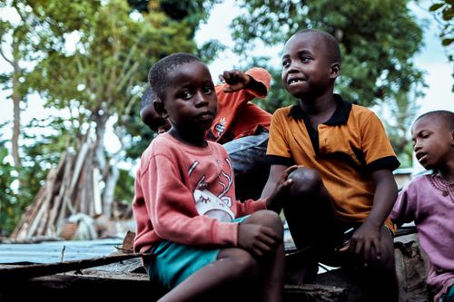 Free Group of African children enjoying playtime outdoors in a village with lush greenery around. Stock Photo
