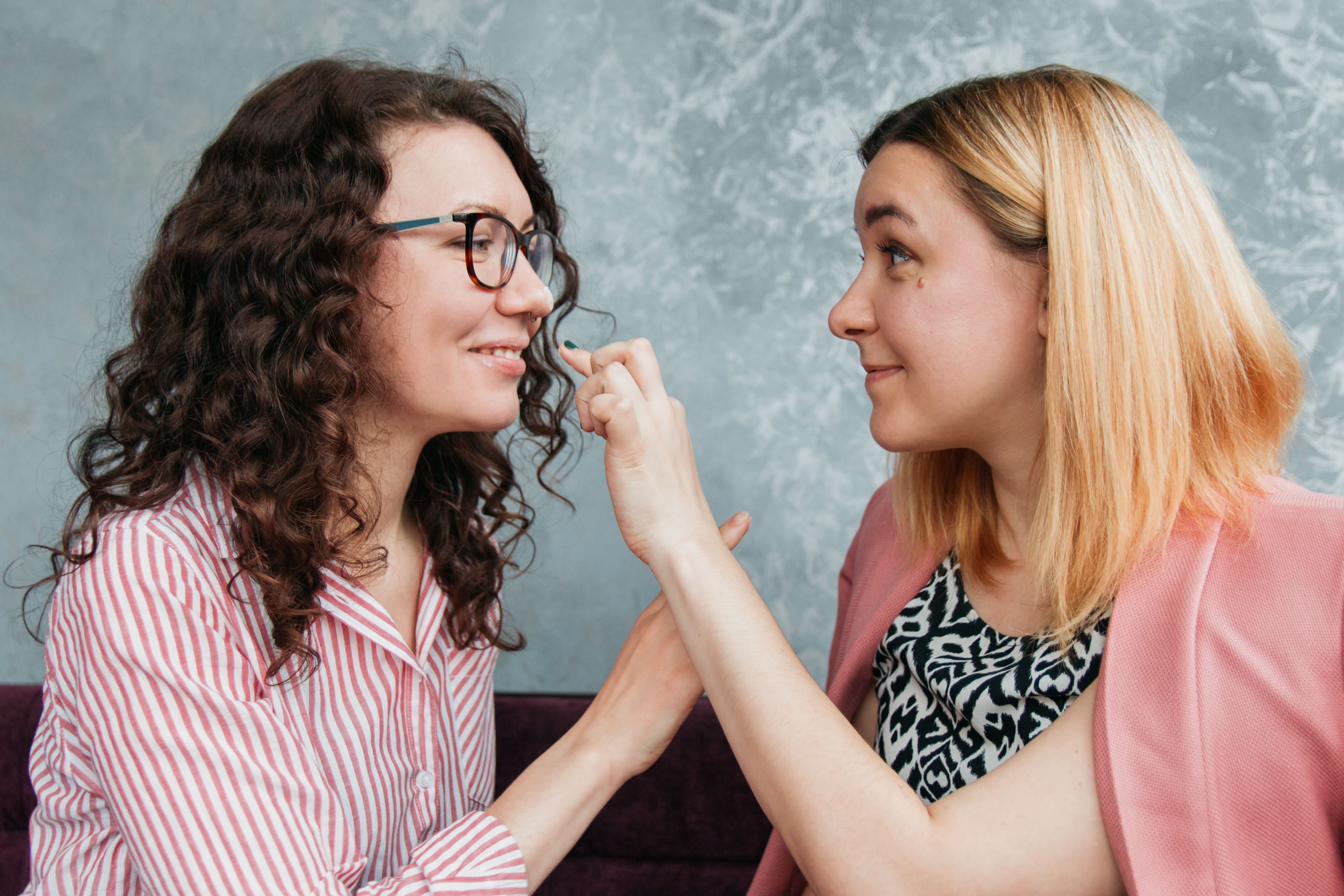 Two women smiling and bonding indoors, showcasing friendship and connection.
