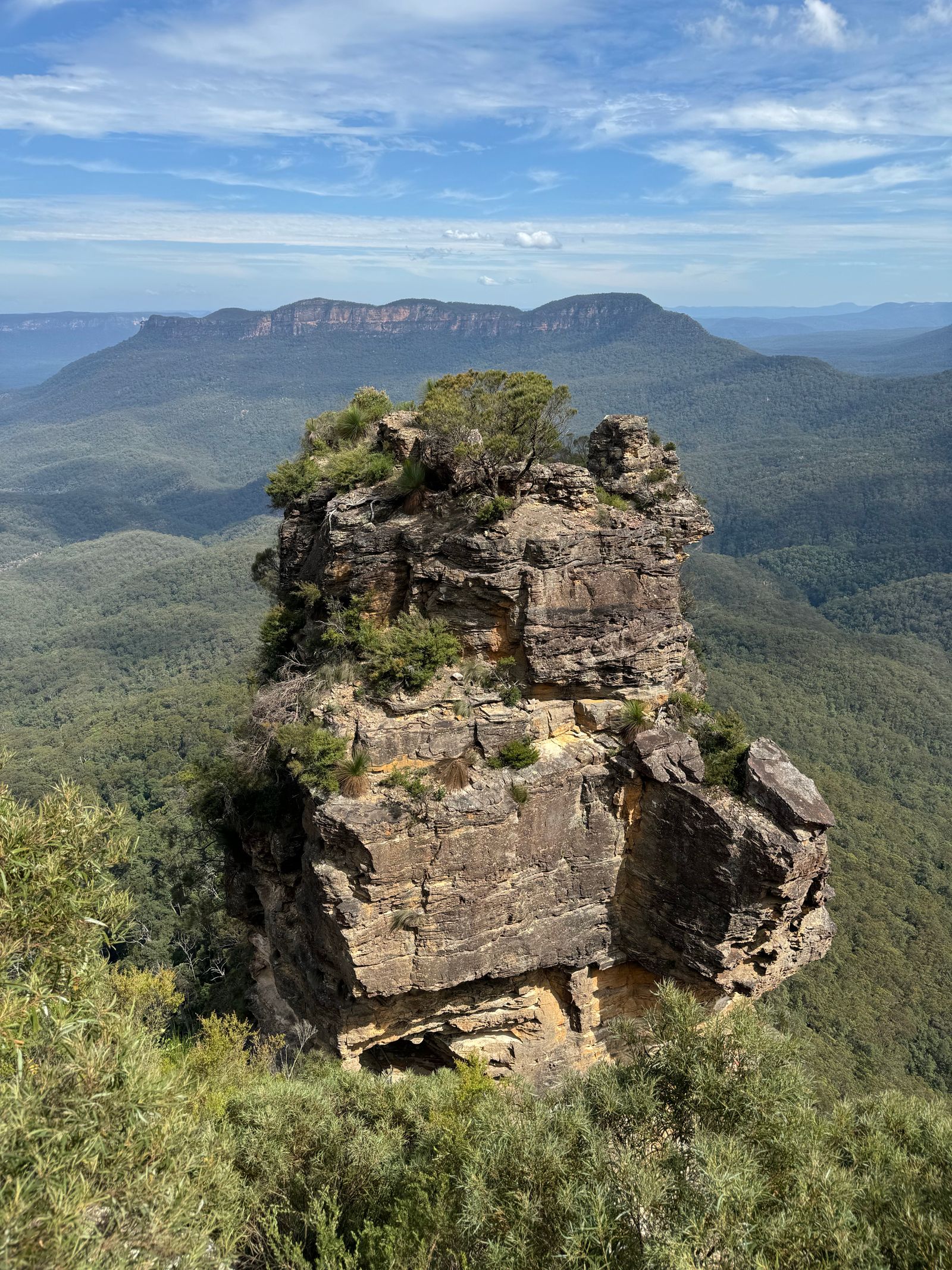 Layered sandstone rock pillar above a blue-hazed eucalyptus valley in the Blue Mountains
