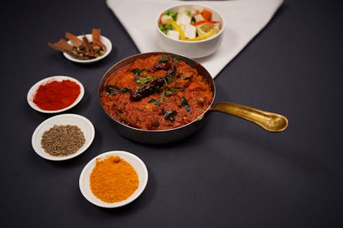 A pan filled with food and bowls of spices