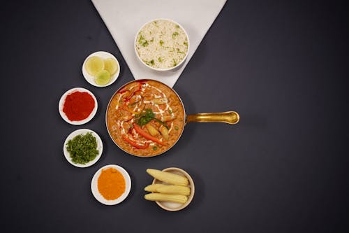 Photo of a Curry Dish Served in a Pan and Bowls with Spices 