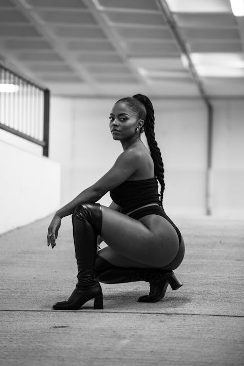A black woman squatting down in a black and white photo