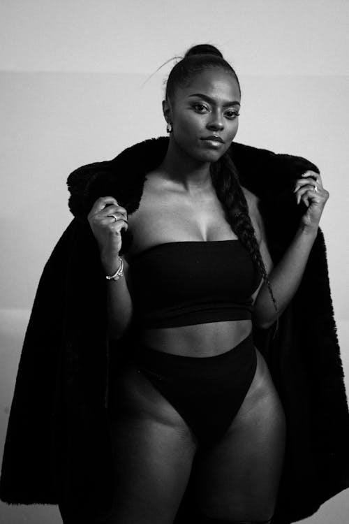 A black woman in a black bikini and fur coat