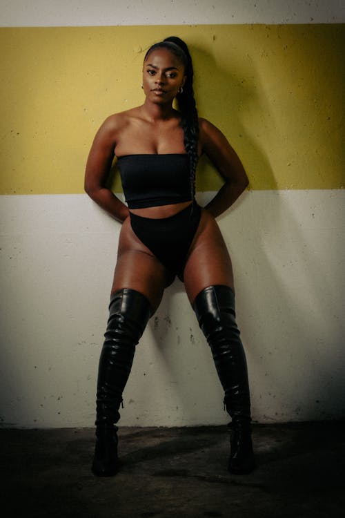 A woman in black and thigh high boots posing