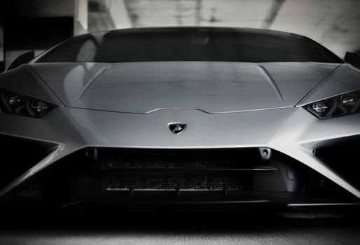 Close-up of a sleek silver Lamborghini Huracan in a parking structure, showcasing its iconic design.