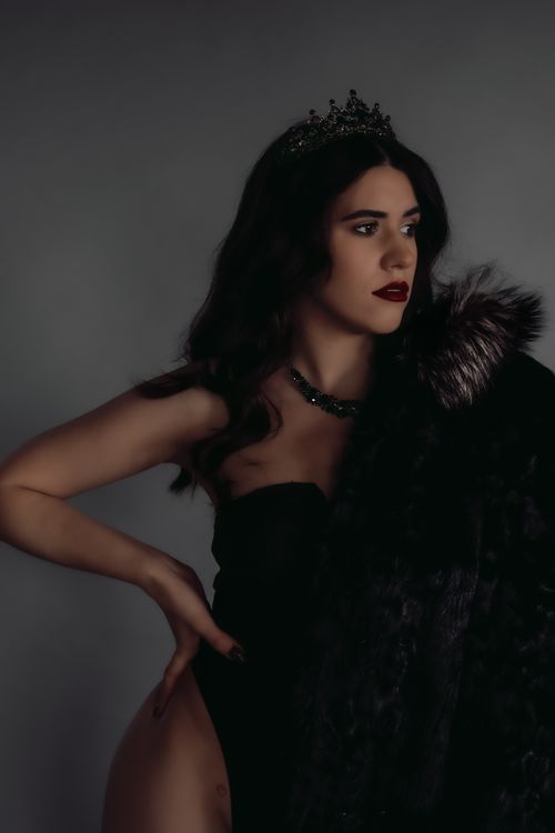 Free Chic portrait of a woman in fur coat and crown against gray background. Stock Photo