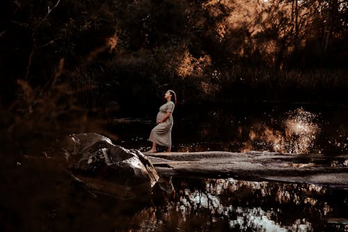 Pregnant Woman Standing on Rock in Forest