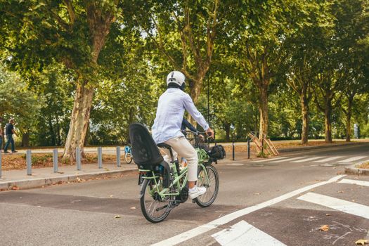 A cyclist rides through a green urban park in Paris on a sunny day.