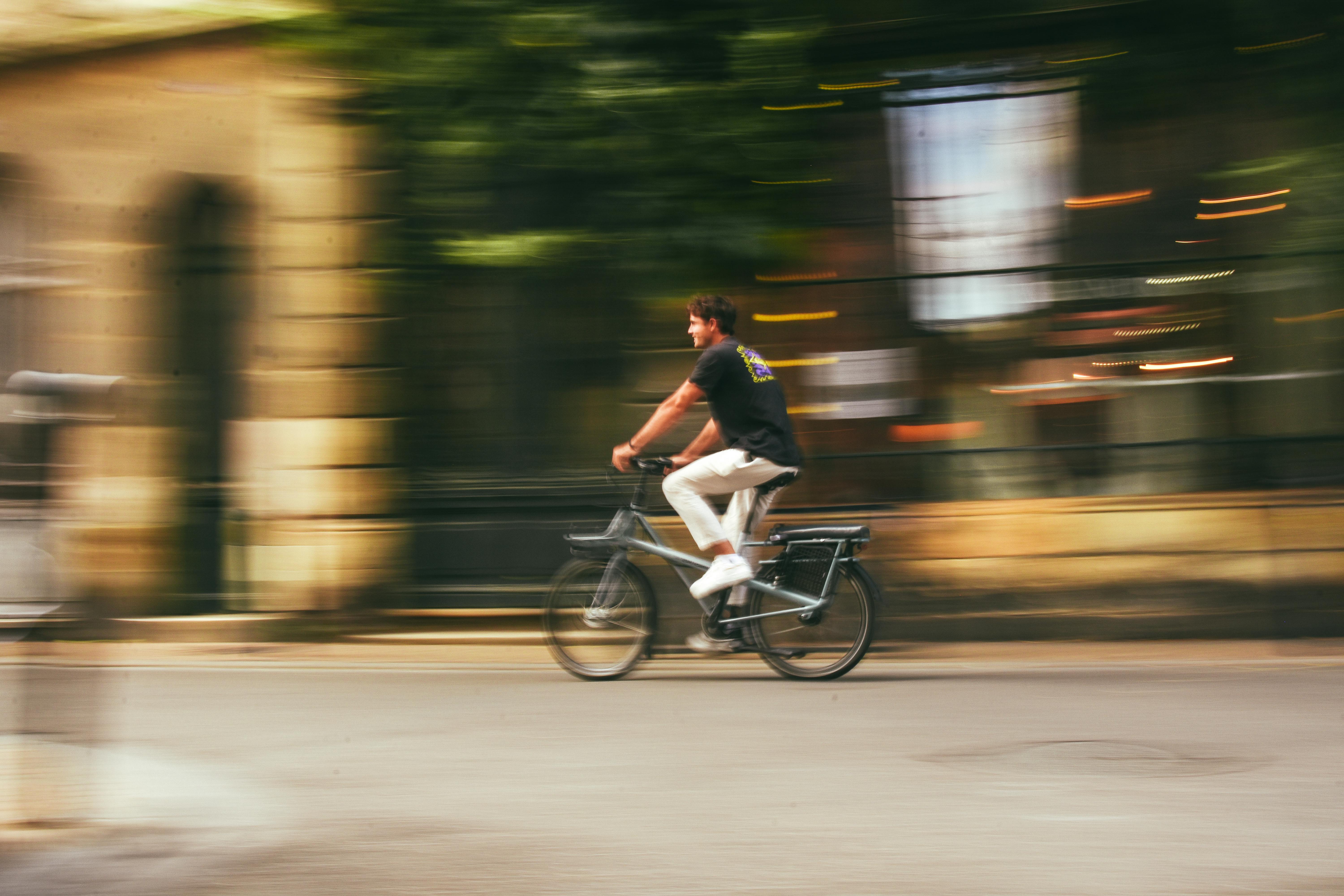 A man riding an electric bike captures motion blur in Bordeaux's urban streets.