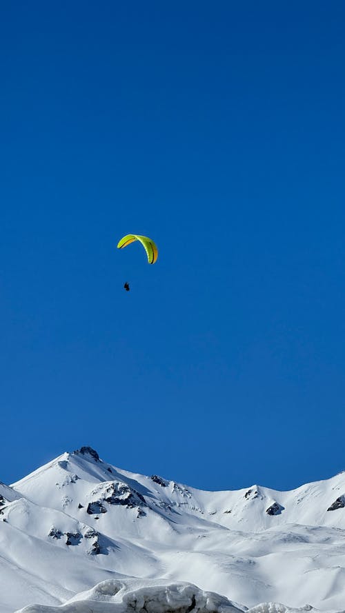 View of a Paraglider Flying above a Snowcapped Mountain 