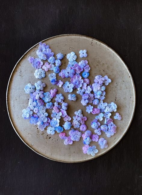 Artistic display of purple and blue embroidered flowers on a vintage tray.
