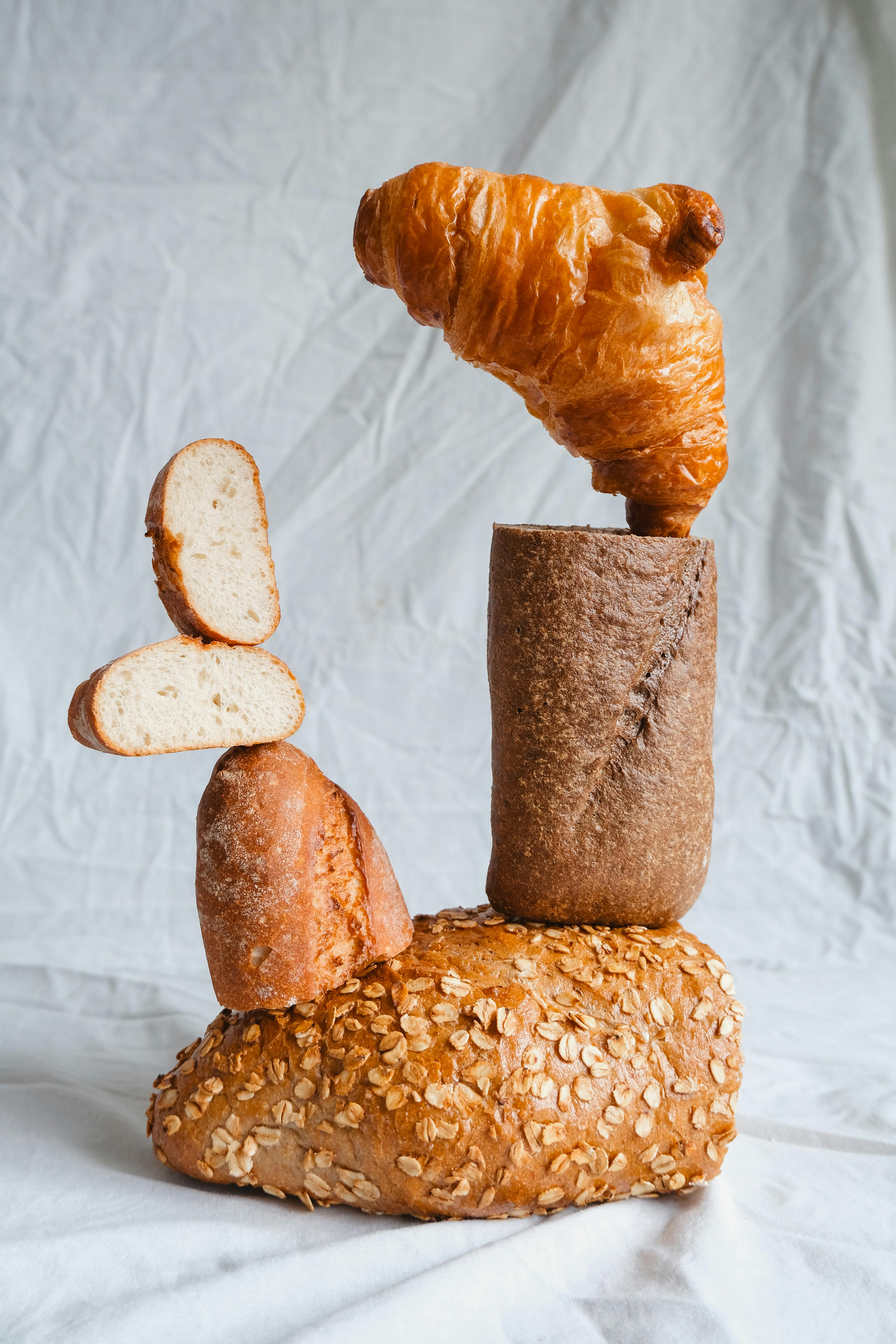 Creative still life of diverse bread types stacked in an artistic composition.