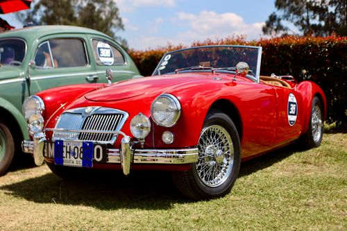 Free Red vintage cabriolet displayed outdoors at classic car rally, showcasing its retro design. Stock Photo