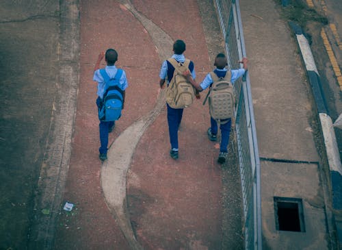 Boys with Backpacks Walking on Pavement